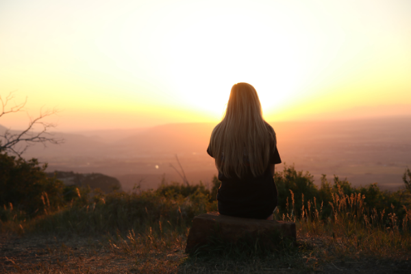 A woman contemplating a sunset over a valley