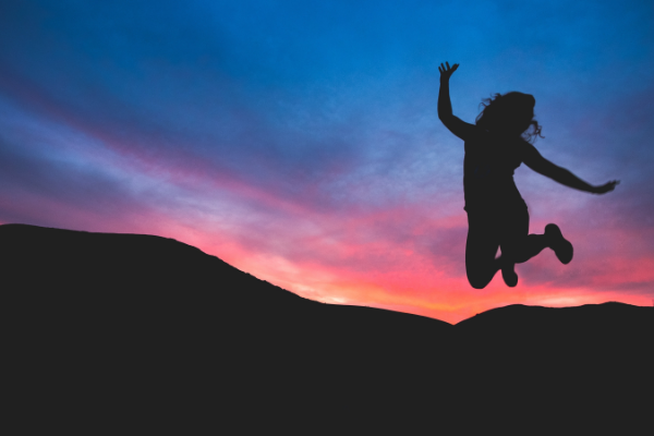 Person leaping for joy against a sunset